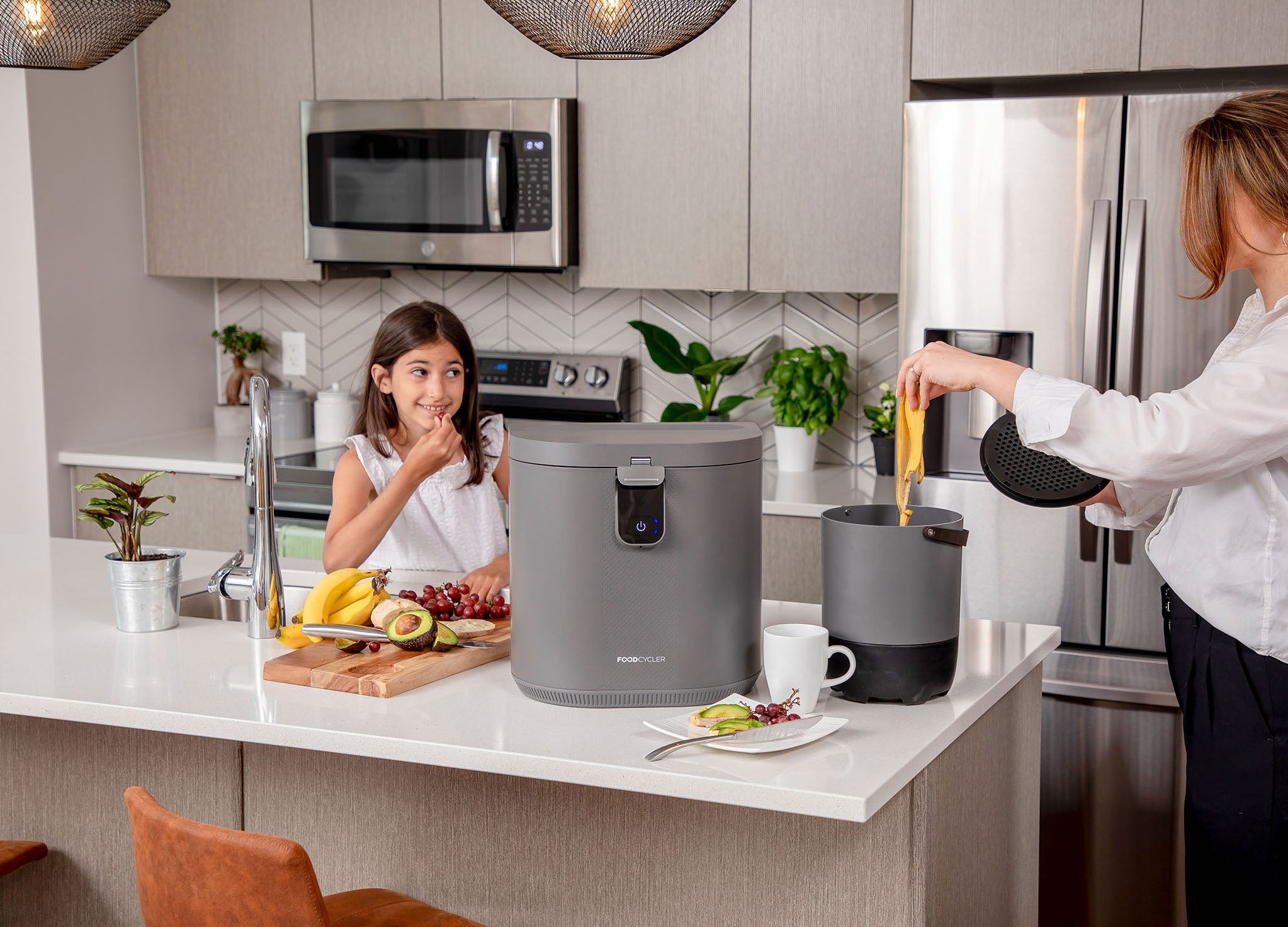 Mother and daughter putting food scraps into their Eco 5; kitchen setting