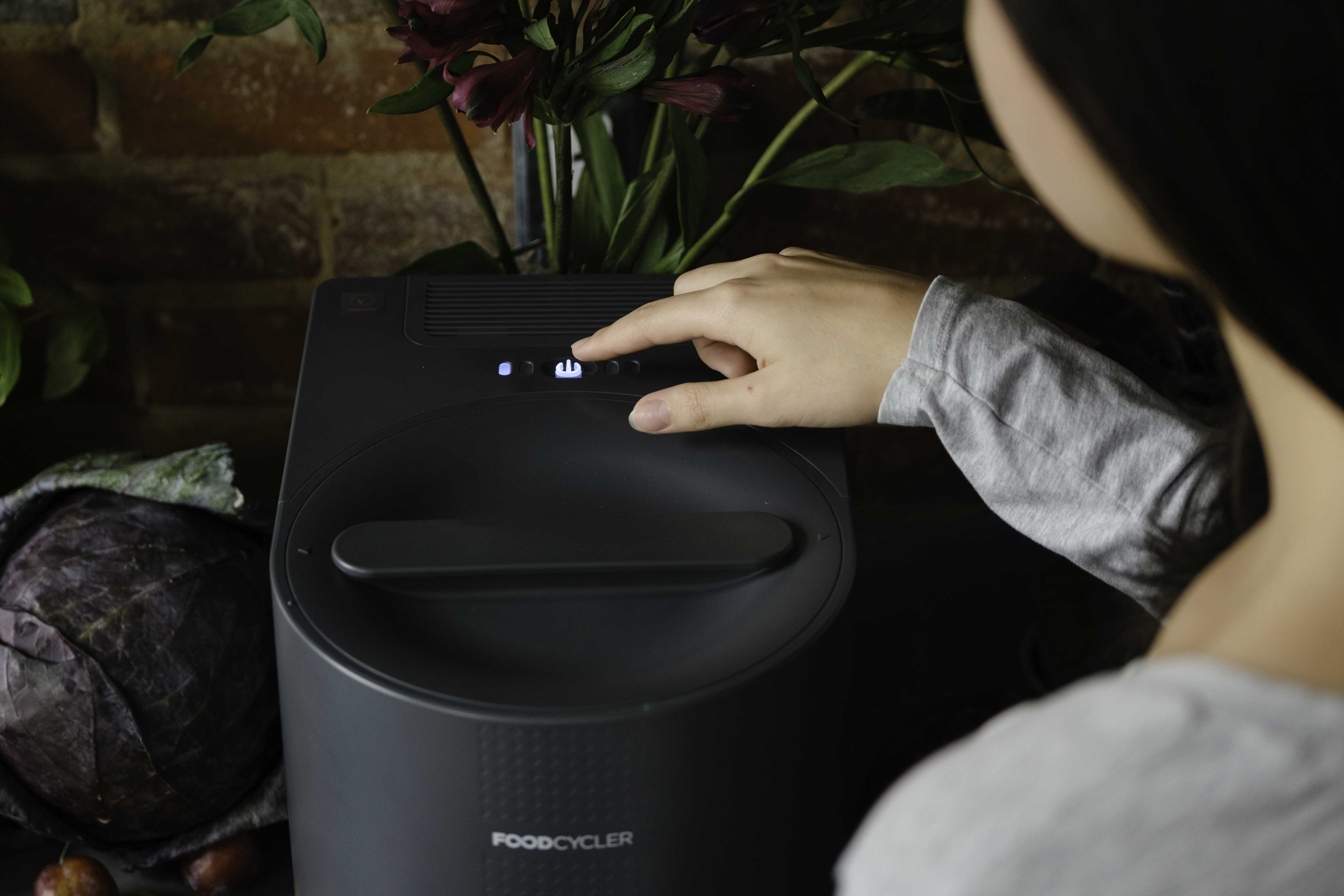 Person turning on the FoodCycler Eco 3 with the push of a button
