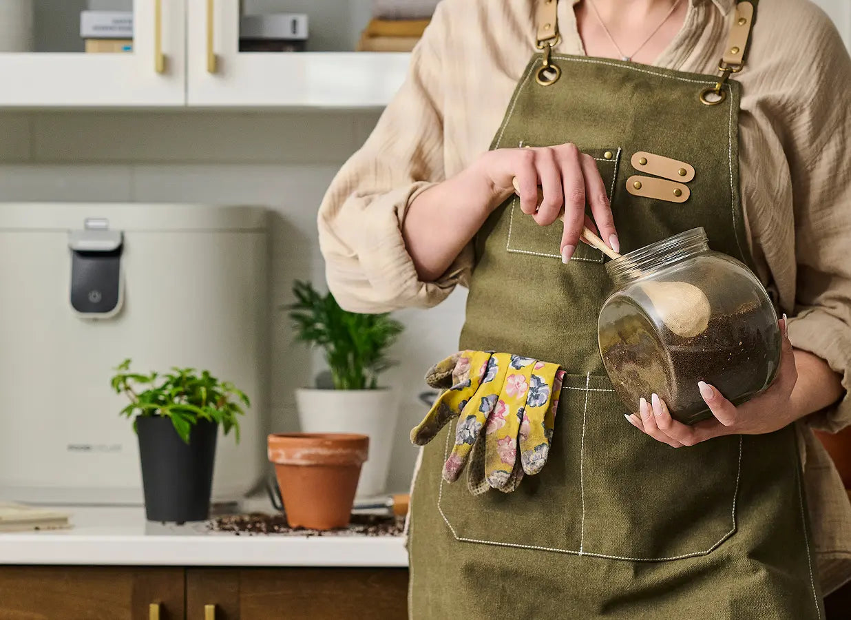 Gardener in a kitchen holding a jar of Foodilizer next to the FoodCycler Eco 5 on a kitchen counter. 