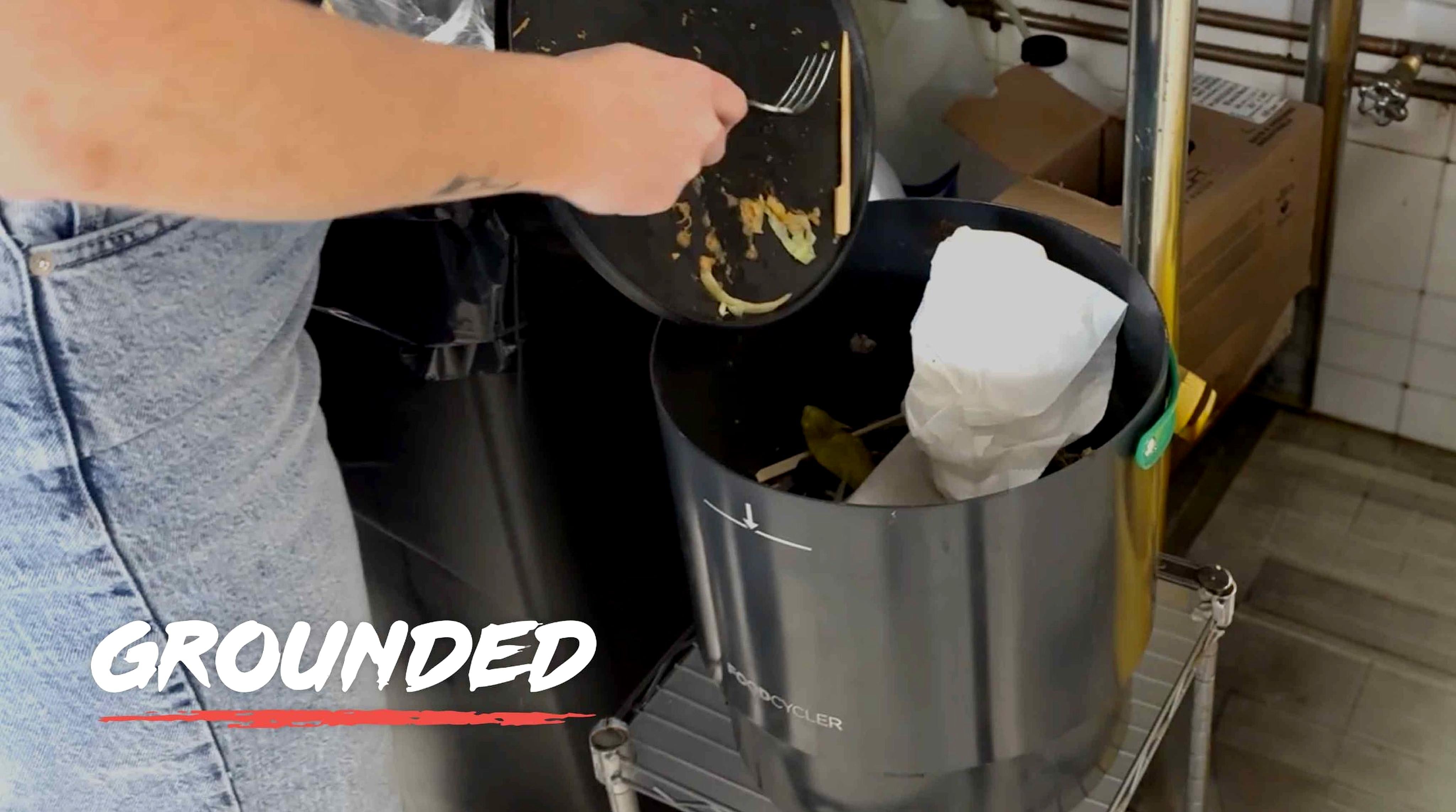 Person adding food scraps to the FoodCycler FC-75 bucket. Overlay text that says, Grounded. 