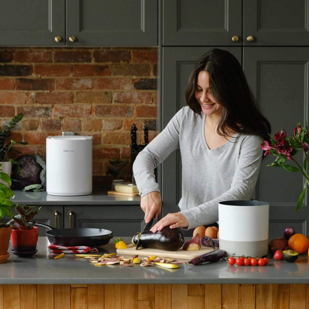 Person cutting veggies with their White FoodCycler Eco 3 along side them.