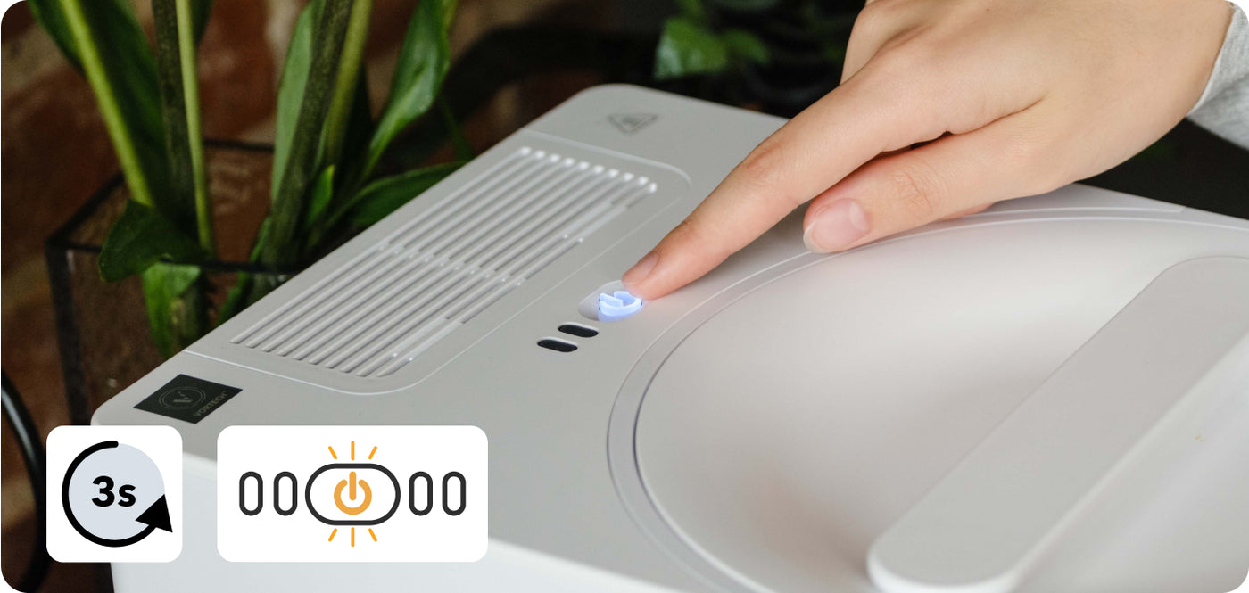 A finger pressing and holding the illuminated Power button on the top of a FoodCycler Eco 3 for three seconds to reset the filter light