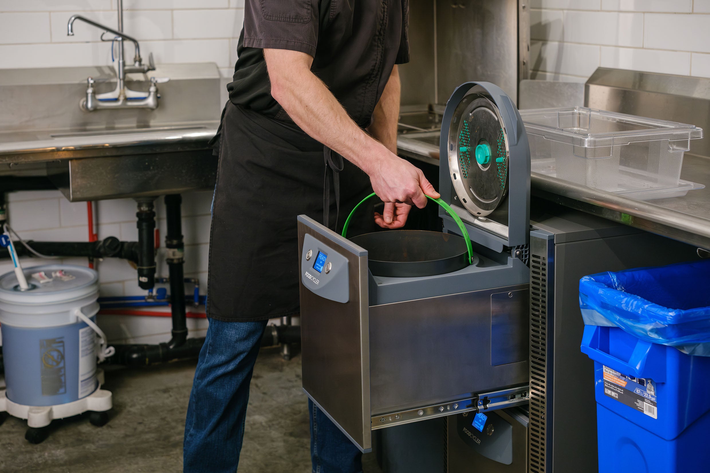 Person removing a bucket of light, dry by-product from the FoodCycler FC-75
