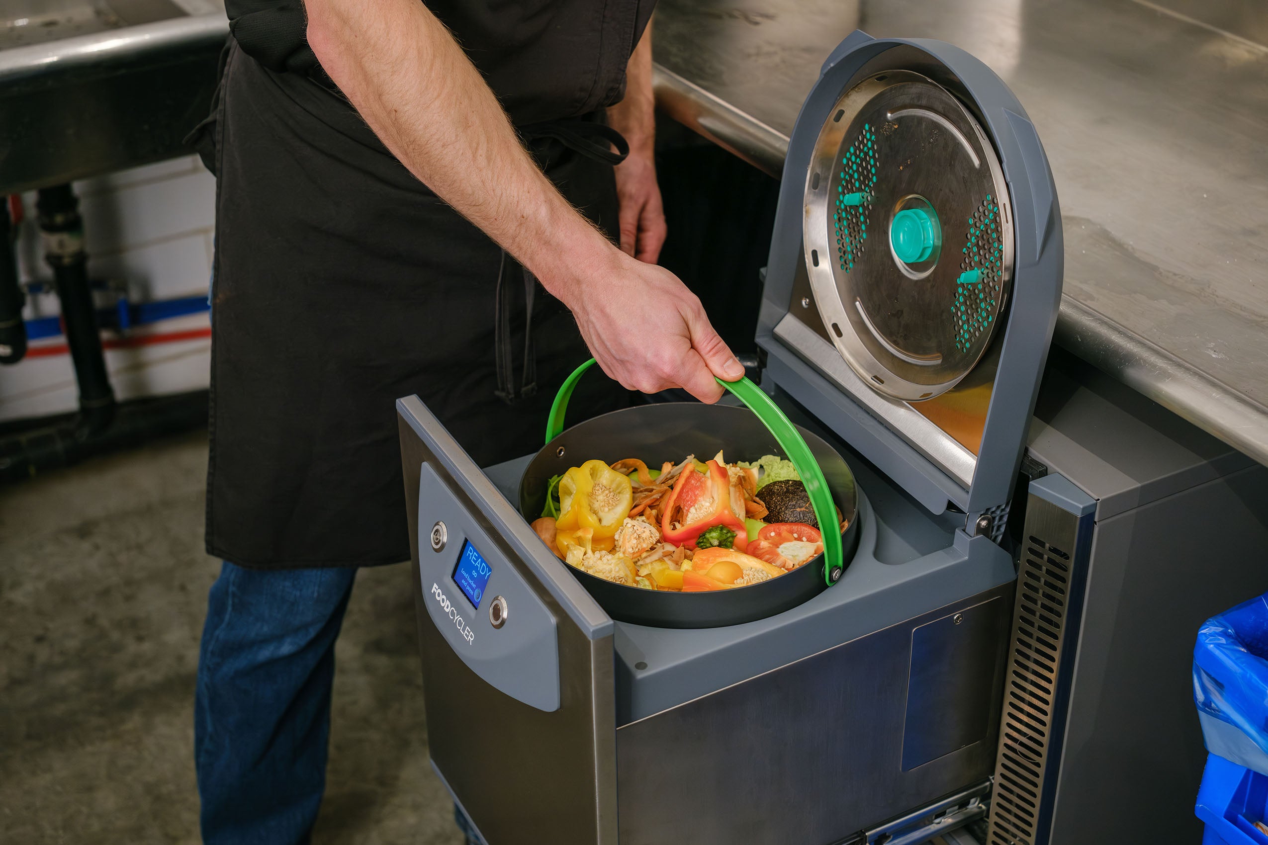 Person placing a bucket of food scraps into the FoodCycler FC-75