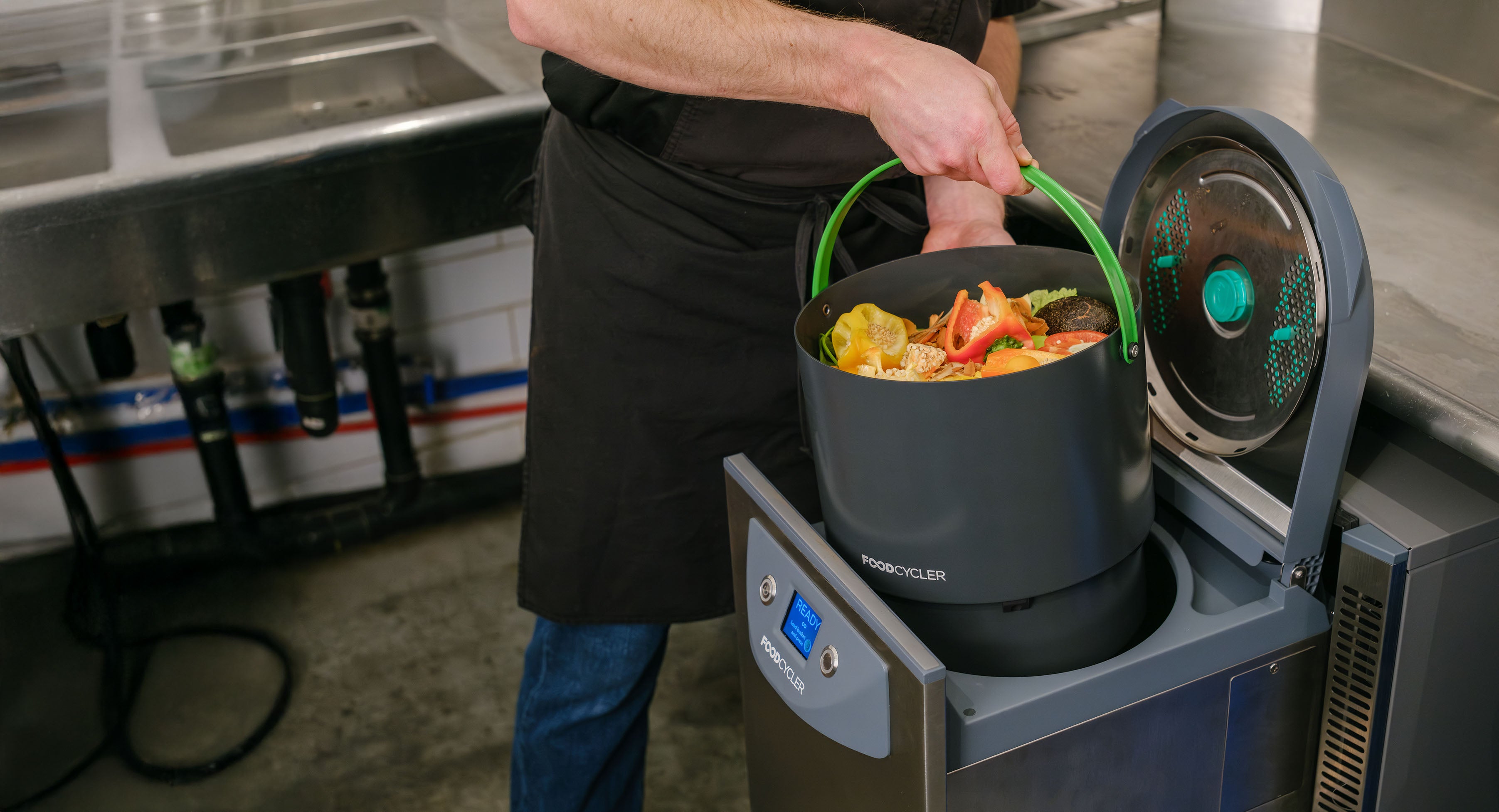 Person loading a full bucket of food waste into the FoodCycler Commercial FC-75